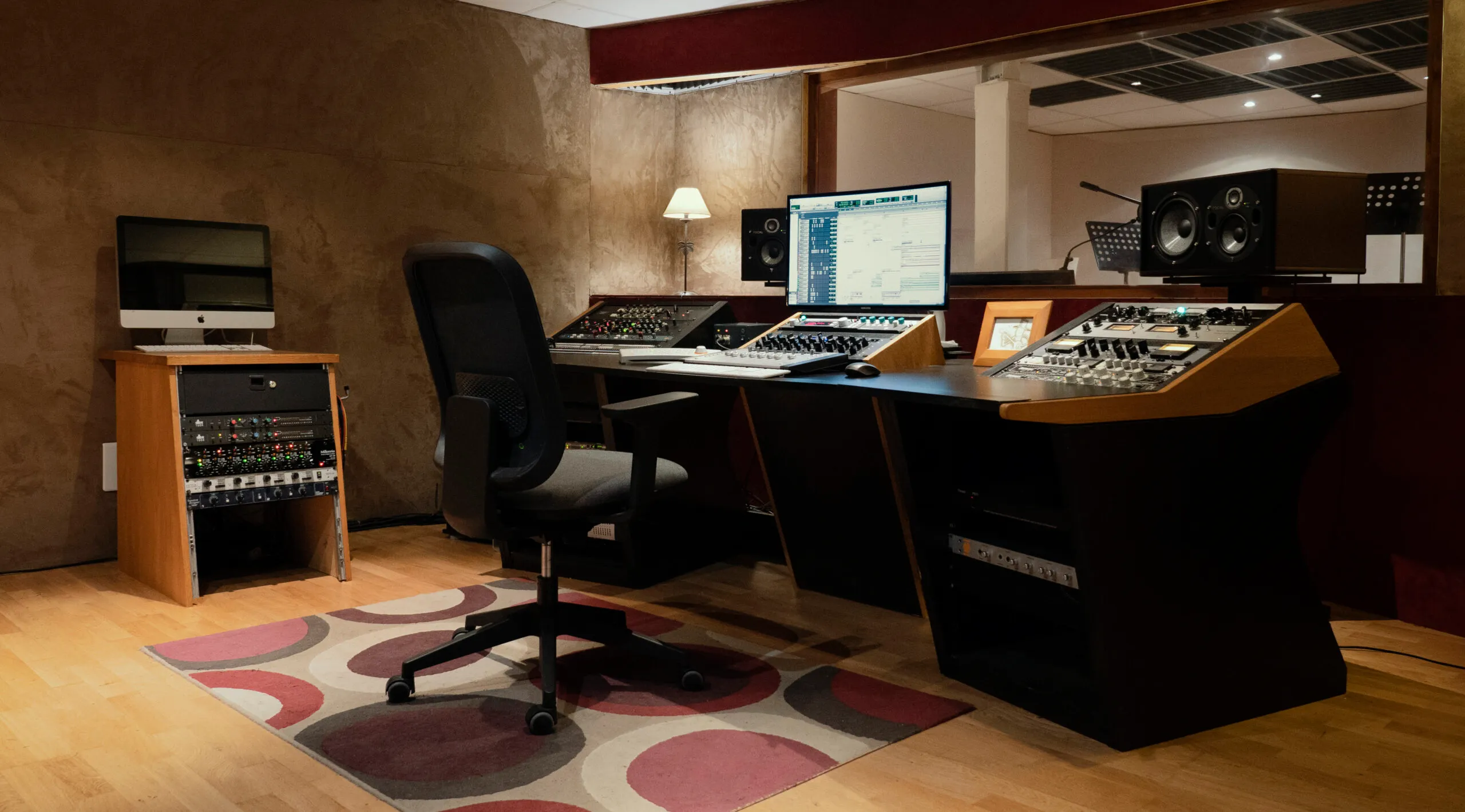 Vue large de la régie : bureau, console, rack de périphériques et enceintes