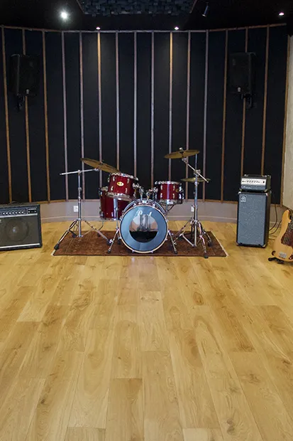 Salle de répétition : batterie et amplis face aux panneaux acoustiques