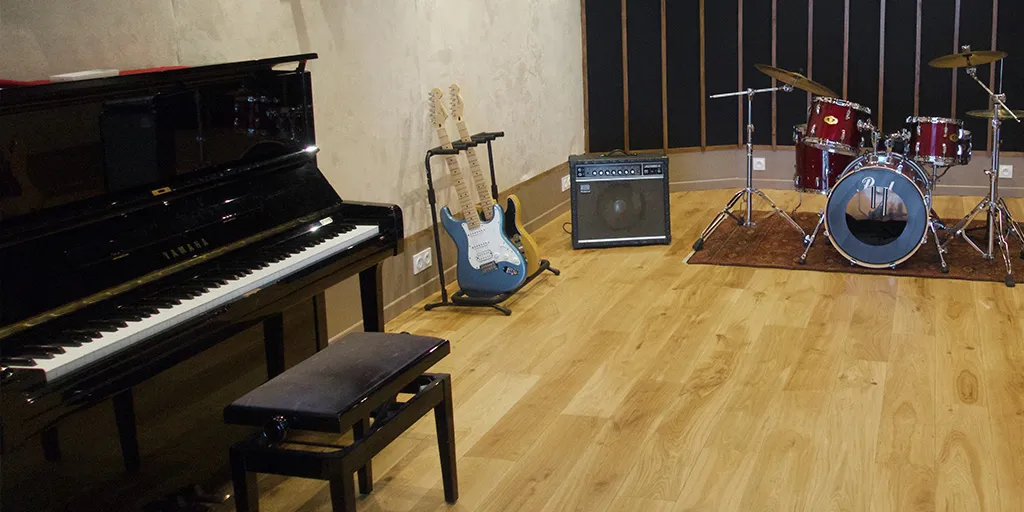 Live room avec piano droit, guitare, ampli et batterie